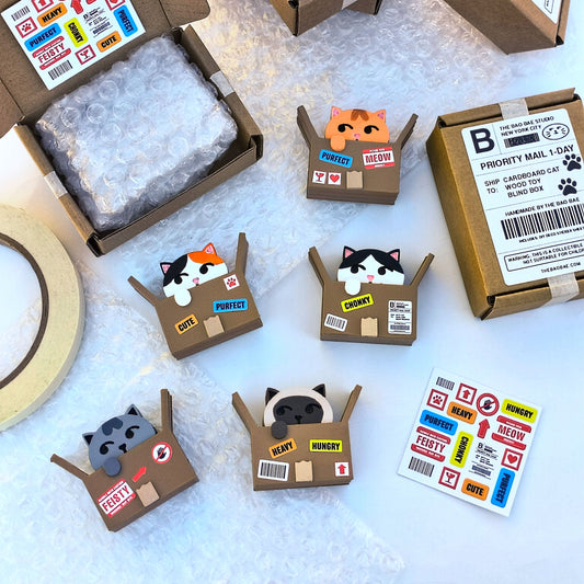 collection of wood toys of cats in cardboard boxes with shipping label stickers