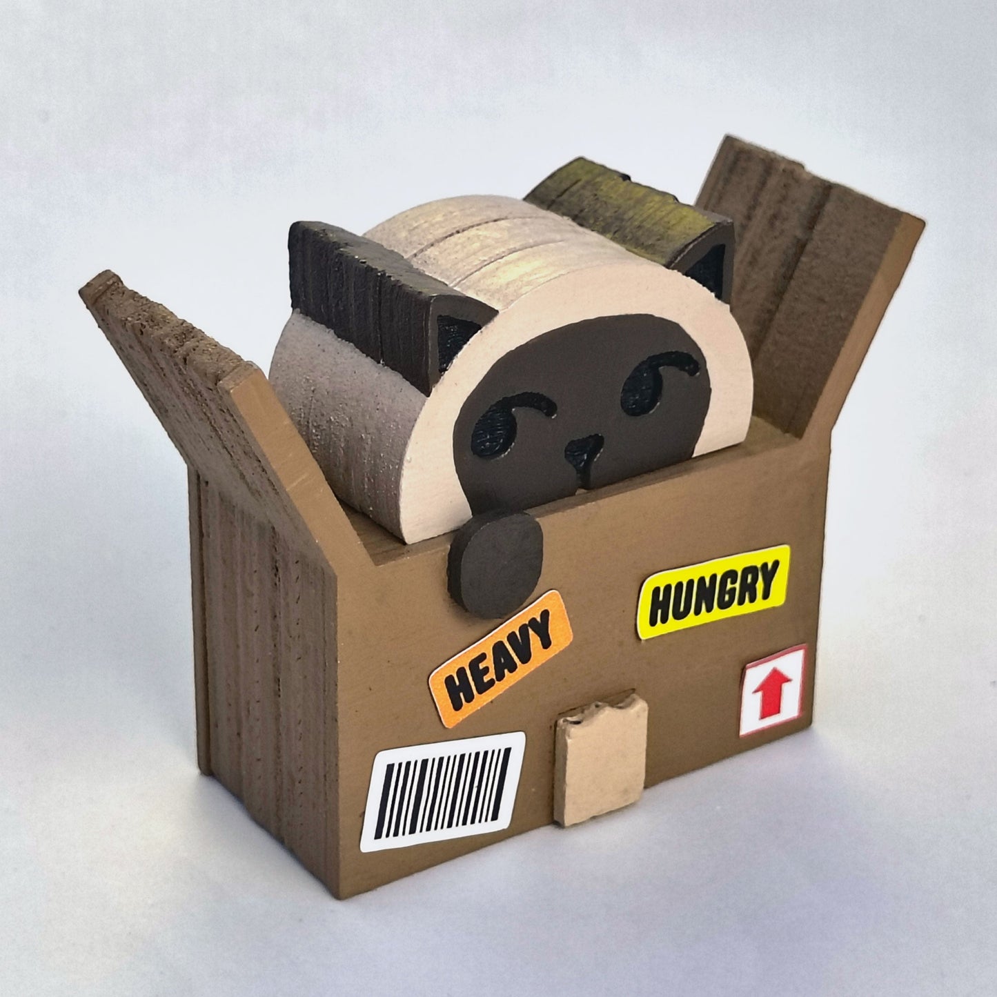 Wood figurine of a siamese cat in a cardboard box with shipping label stickers that say "heavy" and "hungry"