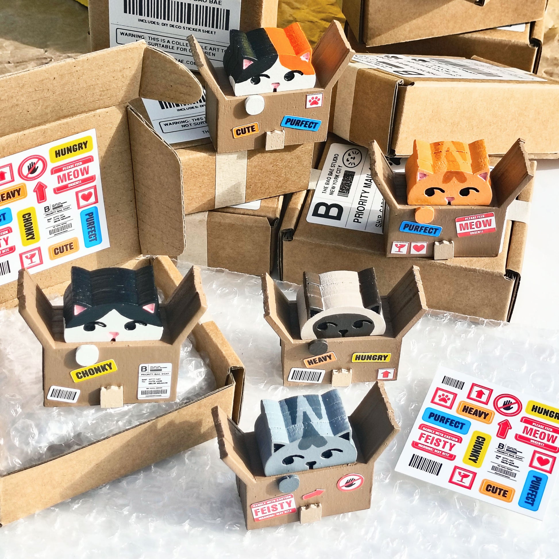 collection of cardboard boxes and wood toys of cats in cardboard boxes with shipping label stickers and a shipping label sticker sheet